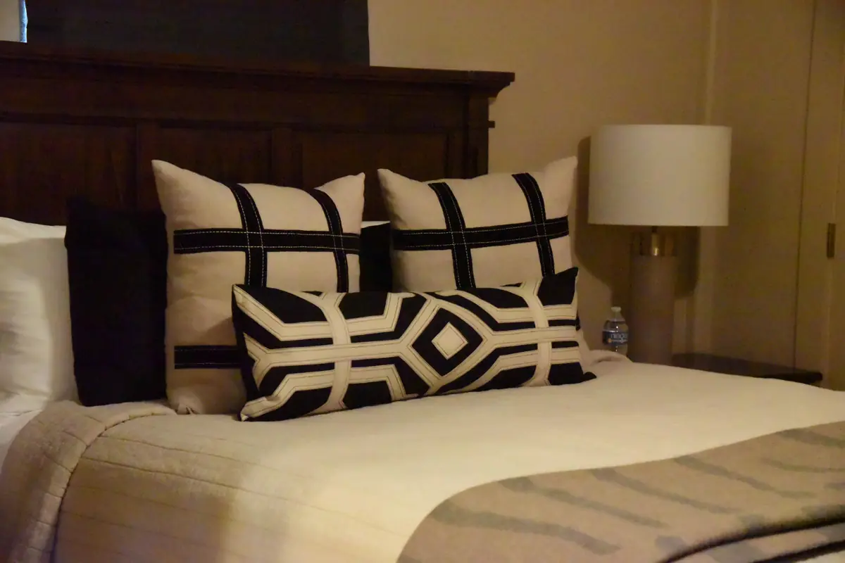 A rustic bedroom with cozy blankets and lots of pillows