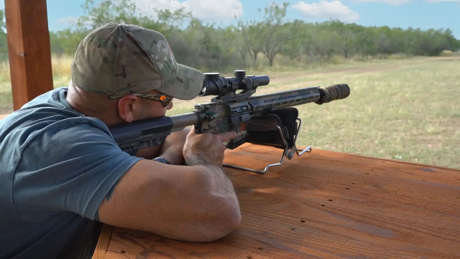 Man with camo hat shoots a gun at a target